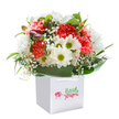 This bouquet captures the lively essence of Holborn itself-an artful gathering of coral, peach, and bright red carnations, each petal softly fringed and full of life, like the bustling energy of local markets. Pure white daisies with golden-green centers offer optimism and contrast, while delicate sprays of baby's breath weave through the arrangement, infusing it with airy innocence. Hints of unopened purple buds tucked on the left add intrigue, evoking curiosity akin to that found wandering the storied lanes of Holborn. Framing everything, broad, deep green leaves arc gracefully around the base, creating a sense of lush abundance and grounding the composition with sophistication. Presented in a simple yet striking white gift bag, its sturdy ribbon handles invite the prospect of an easy handoff-perhaps to a loved one or esteemed friend in the heart of the city. Perfect for birthdays, thank-you gestures, or spontaneous acts of kindness, this bouquet embodies the fresh, contemporary spirit synonymous with Holborn's finest florists, delivering not just flowers, but the gift of an urban moment joyfully shared.